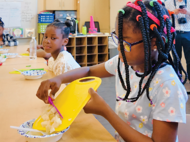 student pushing cut food into bowl